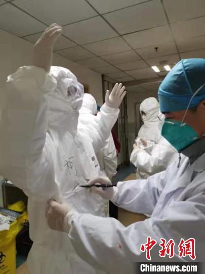 江西援鄂医疗队队员互相在对方的医疗防护服上写上名字。(受访者供图) 刘占昆 摄