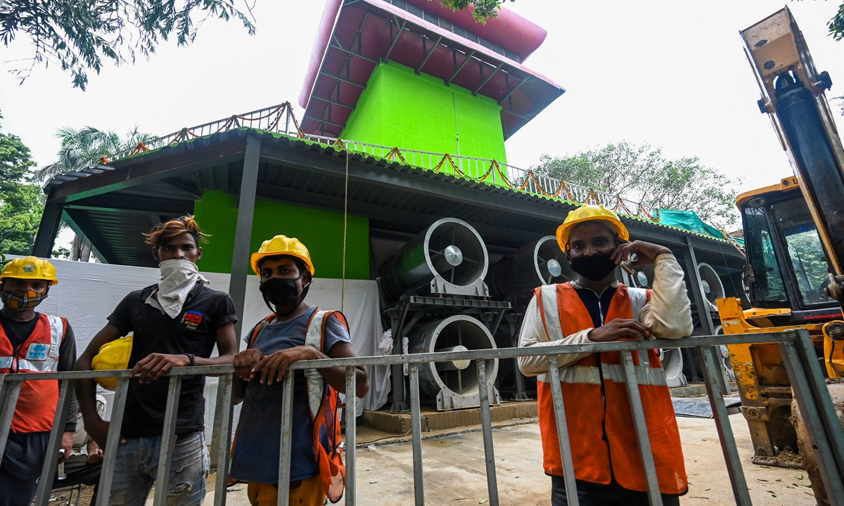 Workers stand in front of a 25-meter-tall smog tower, built to purify air during pollution season, in New Delhi, India on Monday. Photo: AFP
